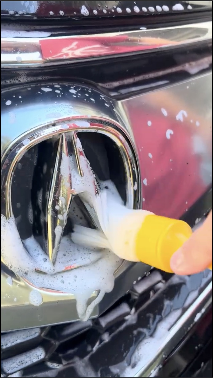 Lowcountry reflection scrubbing the front logo on an Acura SUV